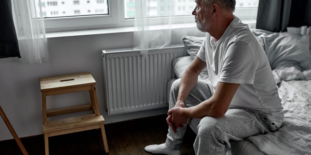 elderly man sitting alone at home, social distancing and self isolation in quarantine lockdown for Coronavirus