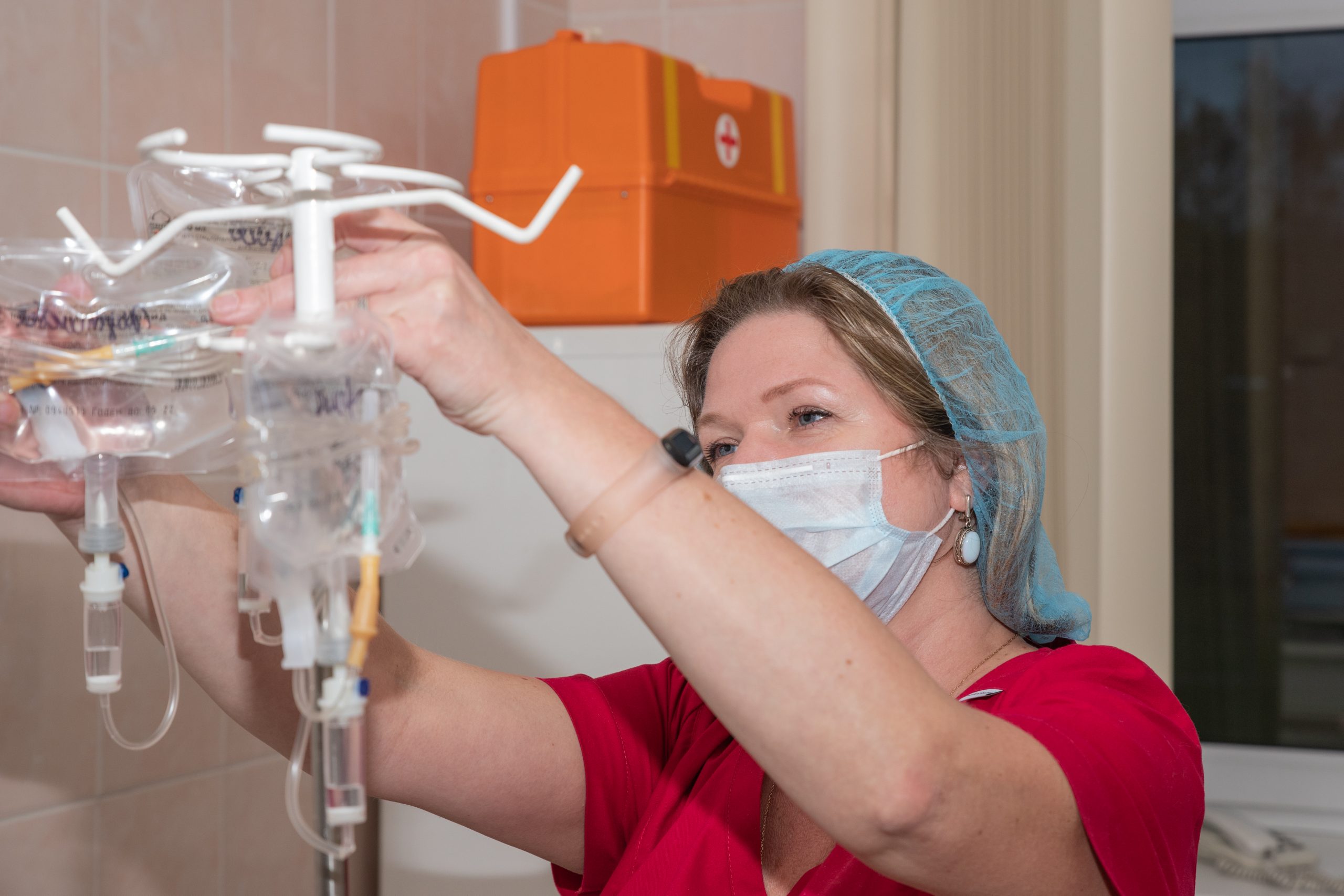 Close-up of a nurse's hand adjusting the physiological serum dropper in a hospital.