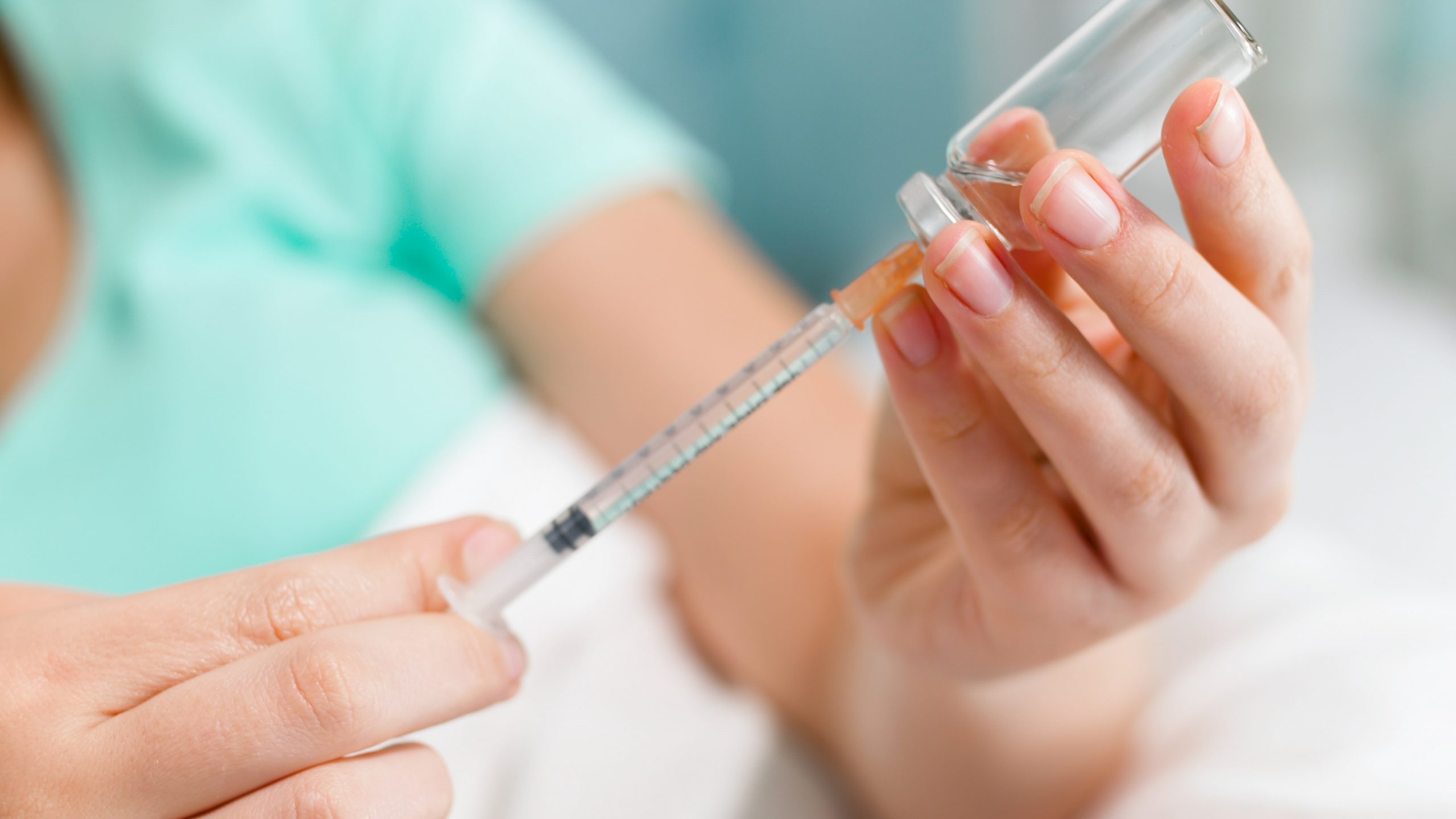 Closeup image of woman suffering from diabetes lying in bed and filling syringe with insulin.