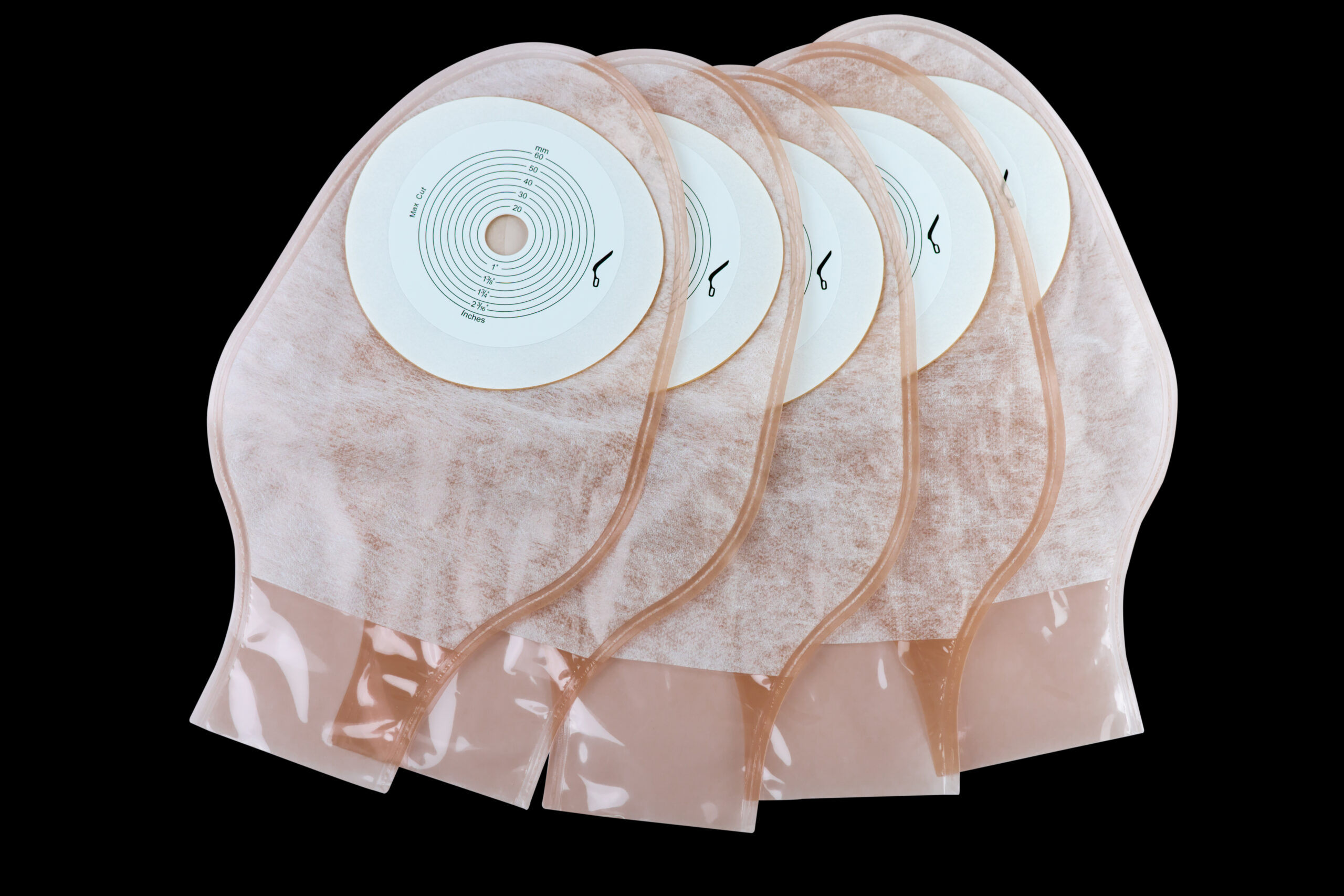 One piece drainable ileostomy or colostomy pouch products isolated on black background. Five pouch stoma care products on dark background. Transparent colostomy bag for colon or rectal cancer patients